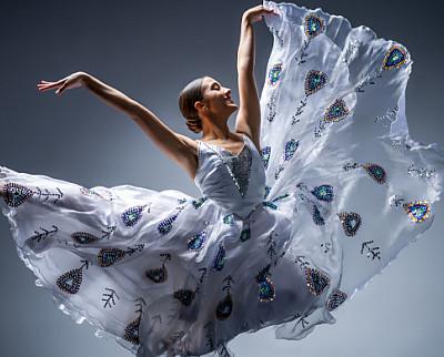 A dancer is a flowing gown leaping in the air.